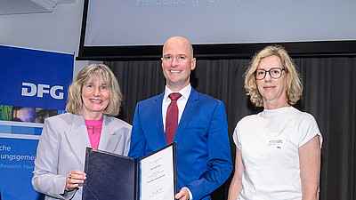 Prizewinner Lukas Bunse (center) with DFG Secretary General Heide Ahrens (left) and laudator Esther von Stebut-Borschitz. Photo: © DFG / David Ausserhofer